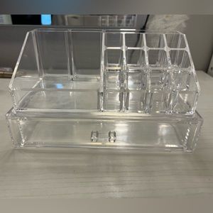 A clear makeup storage container with a drawer